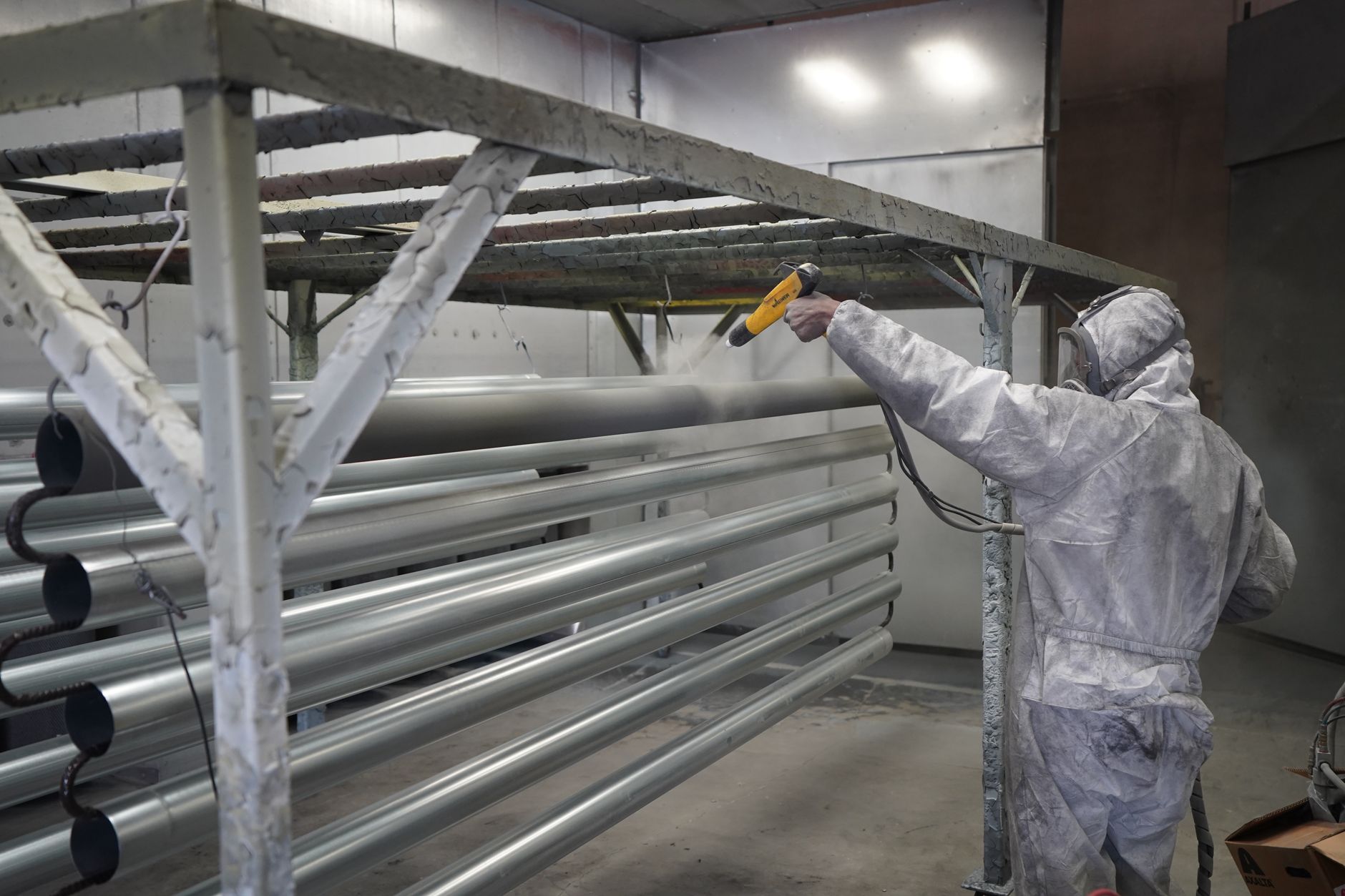 Worker in protective gear finishing metal pipe in a workshop