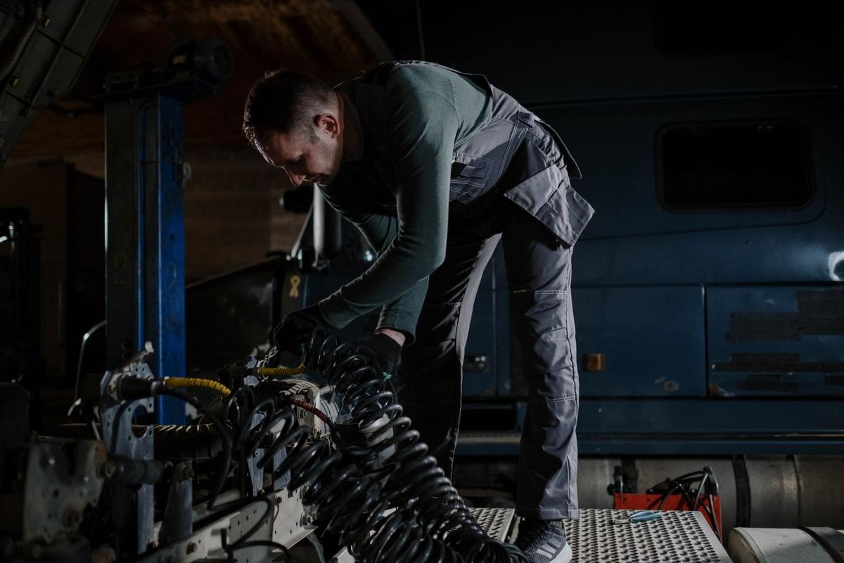Mechanic working on a heavy truck engine in a workshop bay