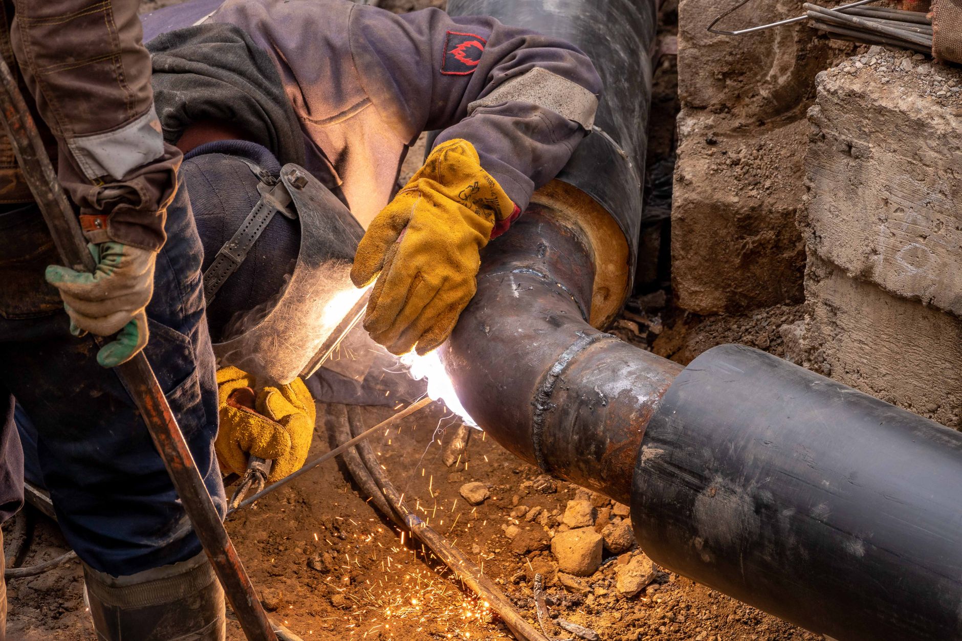 Welder joining steel pipe in an industrial setting